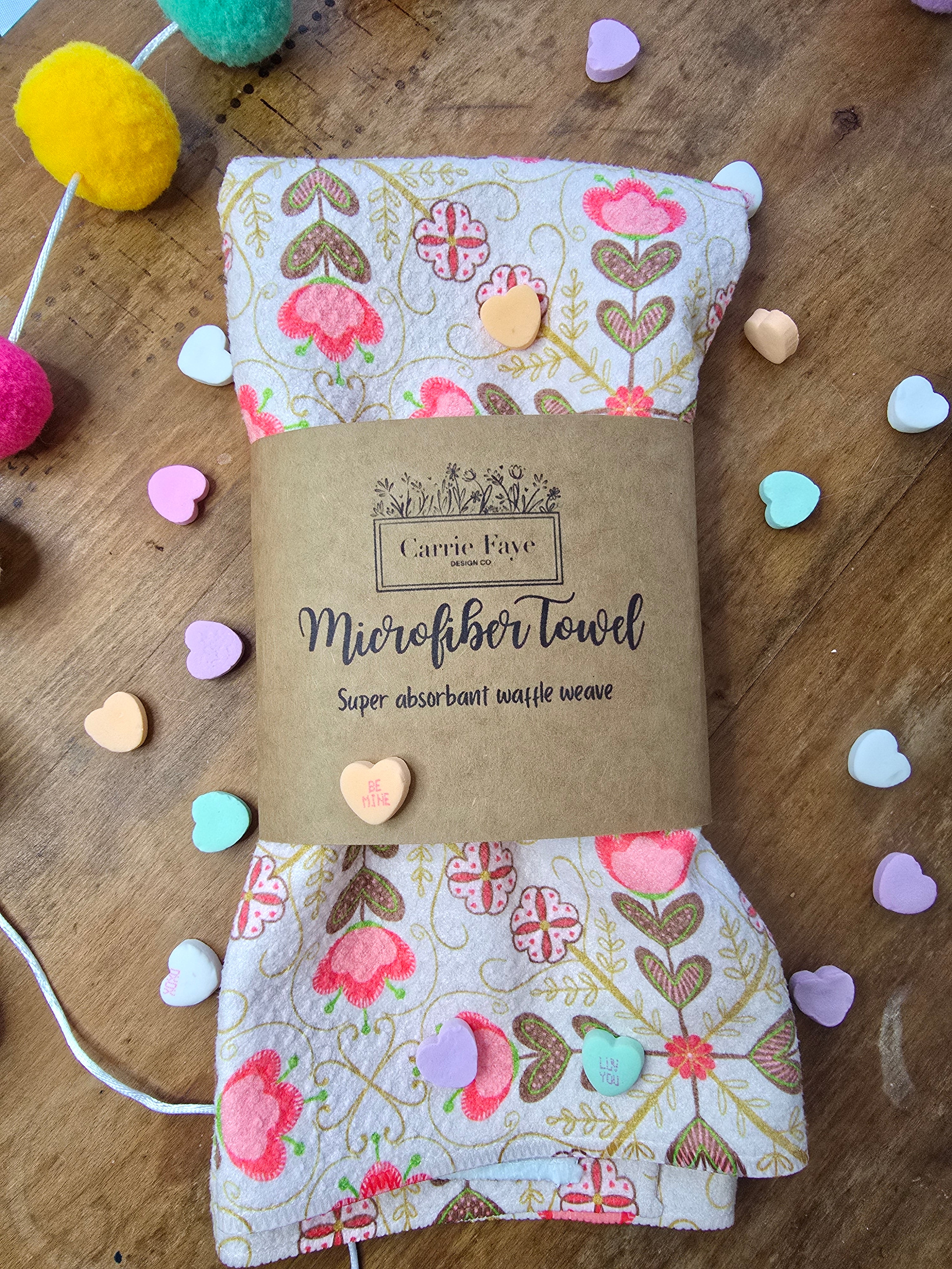 Floral-patterned hand towel with a brown label on a wooden surface.