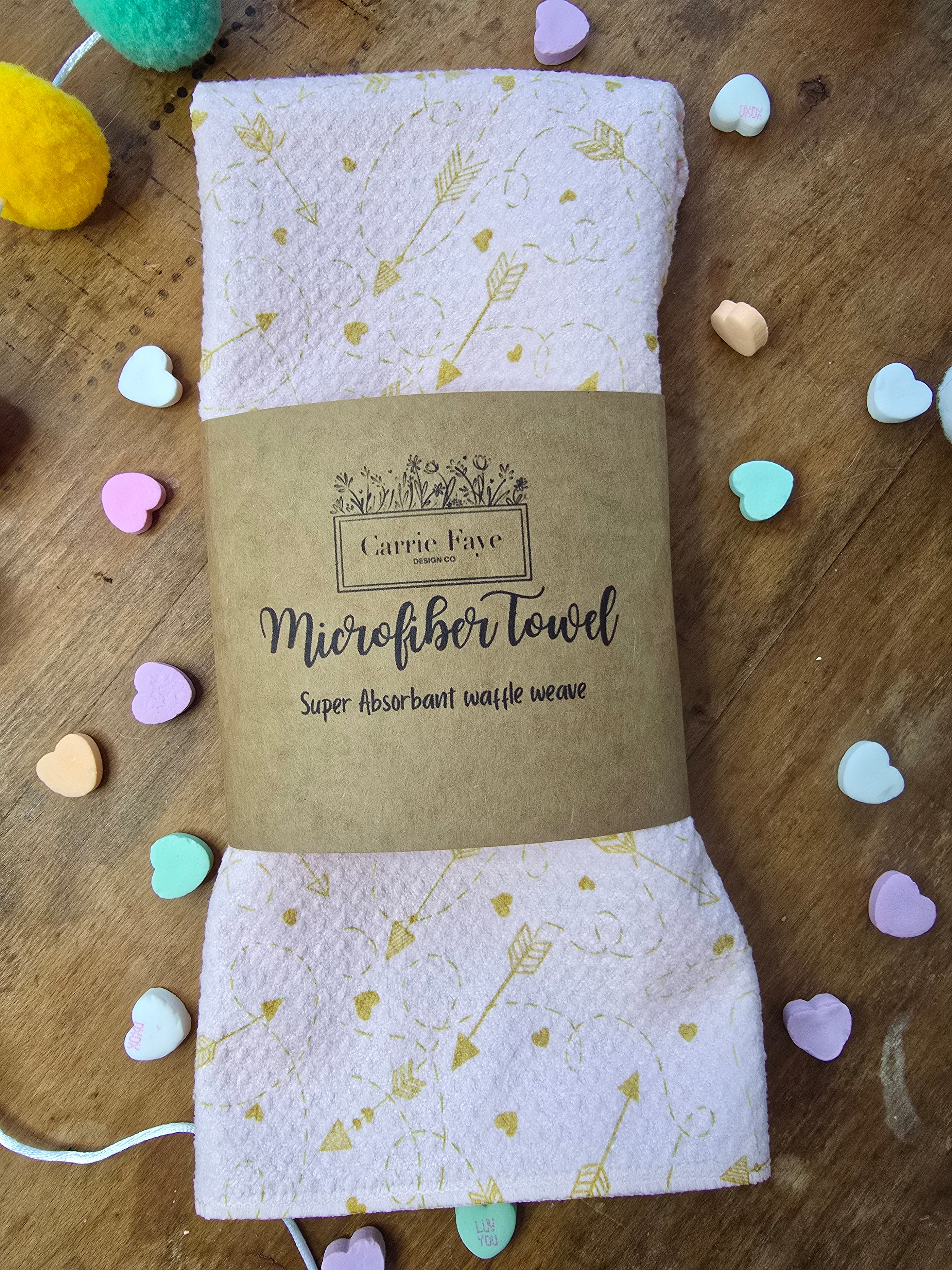 a microfiber towels with a branded label on a wooden surface with heart-shaped candies.